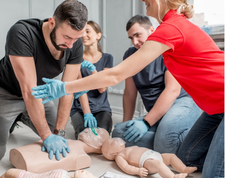 Stagiaire pratiquant un massage cardiaque sur un mannequin avec l’aide d’une formatrice SST